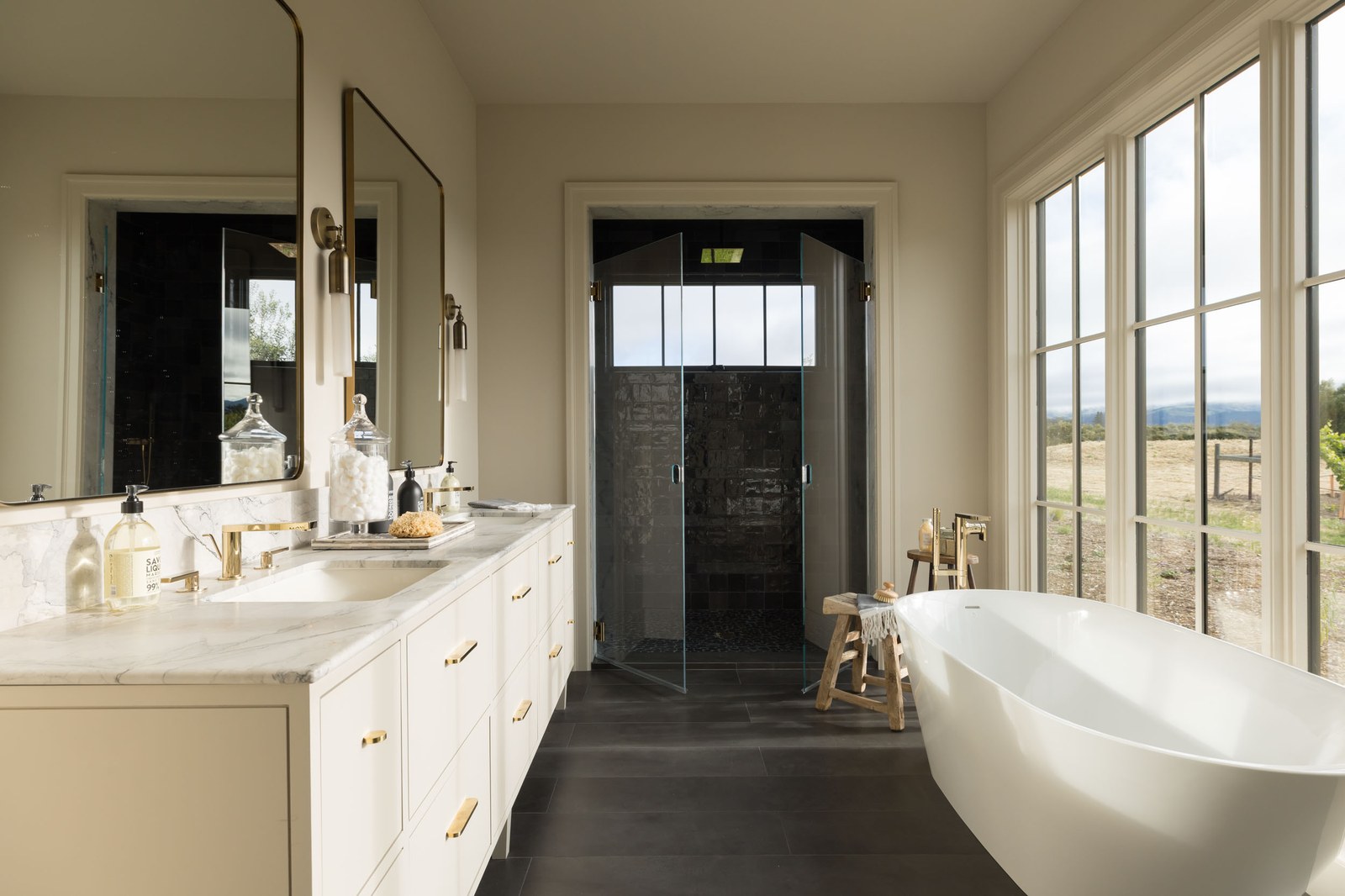 Primary bathroom with marble, brass fixtures, and freestanding tub